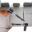 Handheld vacuum cleaner being used on car back seat upholstery